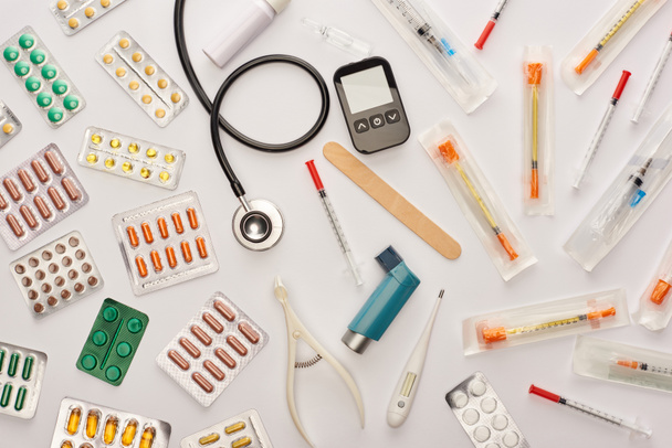 Vista superior de píldoras, jeringas y objetos médicos sobre fondo blanco
 - Foto, Imagen