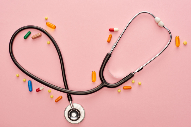 Top view of colorful pills with stethoscope on pink background  - Fotoğraf, Görsel