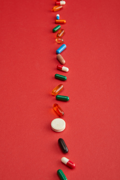 High angle view of bright pills on red background - Foto, Imagen