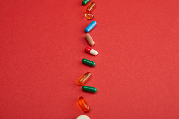 High angle view of colorful pills on red background - Фото, зображення
