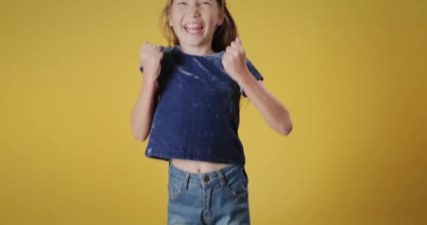 Portrait of happy caucasian little girl smiling, looking at camera. Redhead female child jumping for happiness with cheerful emotions and feelings of joy. Copy space, slow motion - Кадры, видео