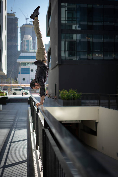 Acrobat keep balance one the hands with blurred Dubai cityscape. Concept of modern, business and unlimited possibility  - 写真・画像