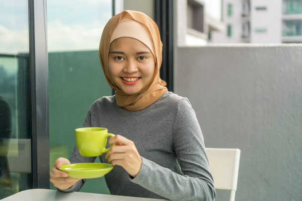 Portraiture of cute malay muslim wearing hijab outdoor holding coffee cup - Photo, Image