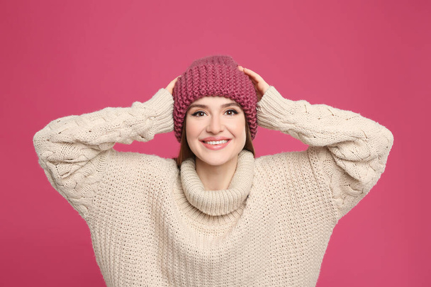 Young woman wearing warm sweater and hat on crimson background. Winter season - Zdjęcie, obraz