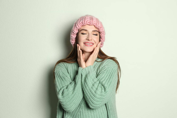 Young woman wearing warm sweater and hat on light background. Winter season - Foto, Imagem