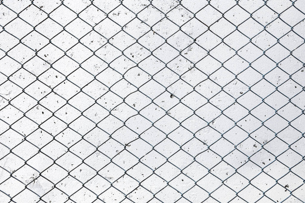 Rete metallica in acciaio per recinzione a catena, sfondo muro di cemento bianco
. - Foto, immagini