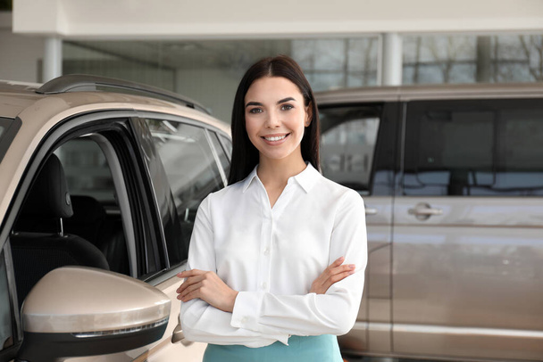 Young saleswoman near new car in dealership - Zdjęcie, obraz