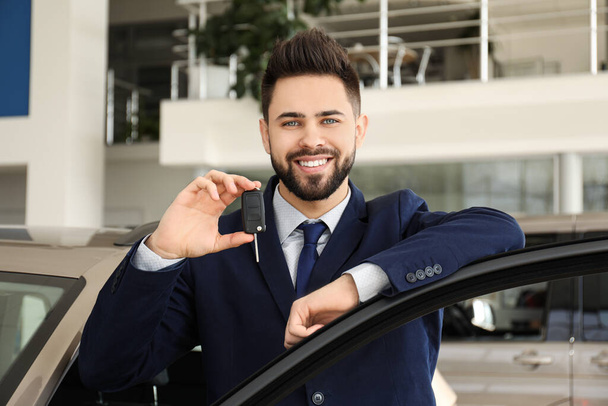 Salesman with key near car in dealership - Photo, Image