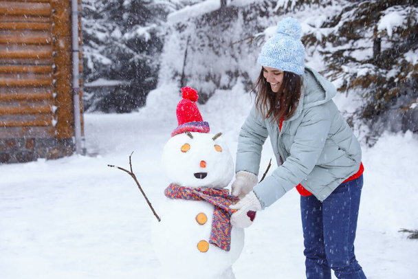 Mulher feliz fazendo boneco de neve ao ar livre. Férias inverno
 - Foto, Imagem