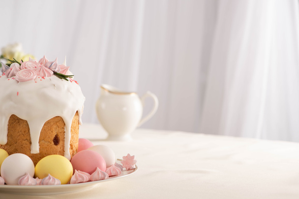 delicious Easter cake decorated with meringue near pink and white eggs on plate - Zdjęcie, obraz