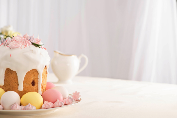 delicioso pastel de Pascua decorado con merengue cerca de huevos de colores en el plato
 - Foto, Imagen
