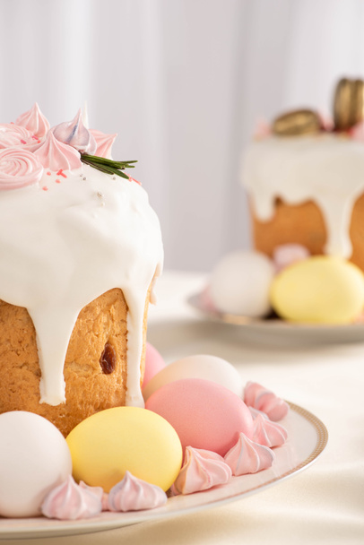 selective focus of delicious Easter cakes with meringue and colorful eggs on plates - Fotografie, Obrázek