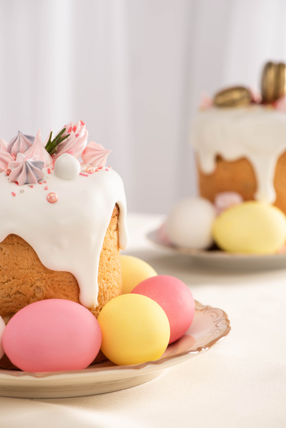 selective focus of delicious Easter cakes with meringue and colorful eggs on plates - Foto, Imagen