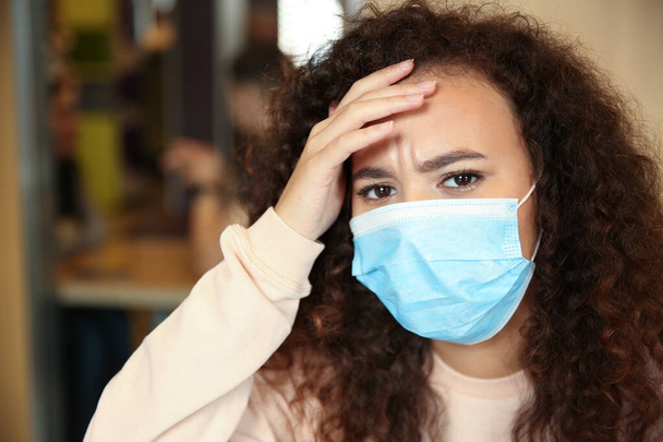 African-American woman with disposable mask in cafe. Virus protection - Foto, Bild
