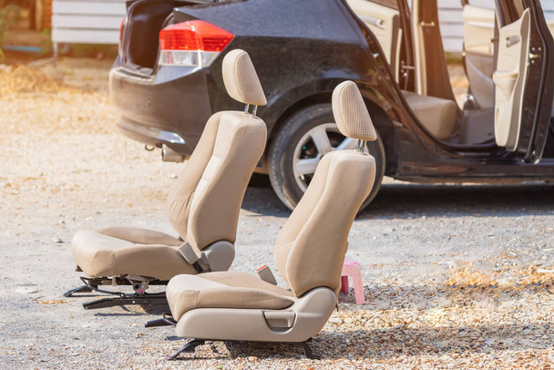Crèmekleurige autostoelen verwijderd uit de zwarte auto voor blootstelling aan de zon en reiniging in de open lucht. - Foto, afbeelding