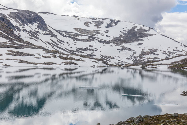 snow mountains surrounded clouds in norwegian fiord reflection in water. selective focus - 写真・画像
