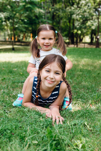 夏の公園の緑の芝生で遊んで横になっている幸せな子供たち - 写真・画像