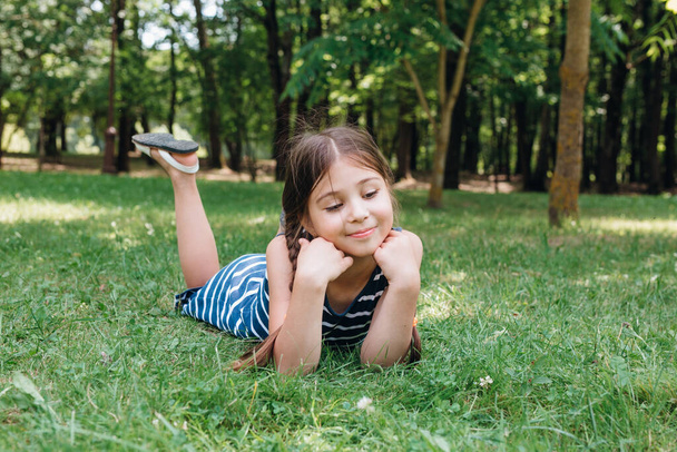 Smiling kid lying on green grass in the park - Photo, image