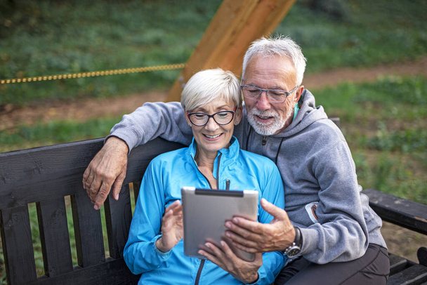 Ηλικιωμένο ζευγάρι με tablet σε δημόσιο πάρκο - Φωτογραφία, εικόνα