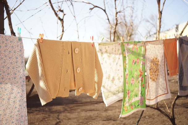 Кухонные полотенца высушиваются на веревке с прищепками в саду
 - Фото, изображение
