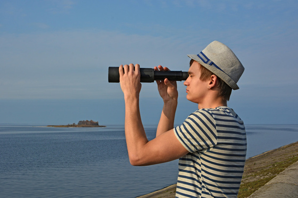 Jeune homme regarde à travers le verre d'espion à la mer
 - Photo, image
