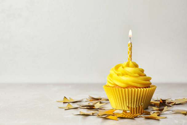 Delicious birthday cupcake with cream and burning candle on table. Space for text - Photo, image