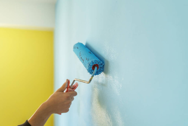 Decorator de hand schilderen muur met roller. - Foto, afbeelding