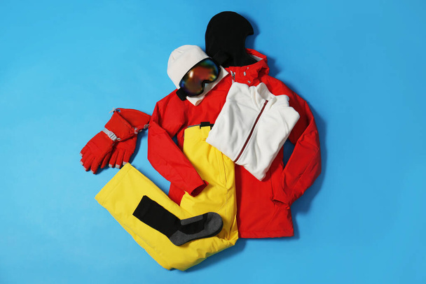 Stylish winter sport clothes on light blue background, flat lay - Foto, afbeelding