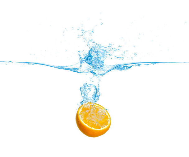 Ripe orange falling down into clear water with splashes against white background - 写真・画像