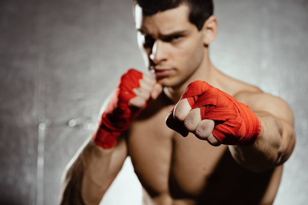 Athletischer Boxer, der mit Entschlossenheit und Vorsicht auf silbernem Hintergrund boxt. Kraft, Angriff und Bewegungskonzept. Fit kaukasisches Modell in Bewegung - Foto, Bild
