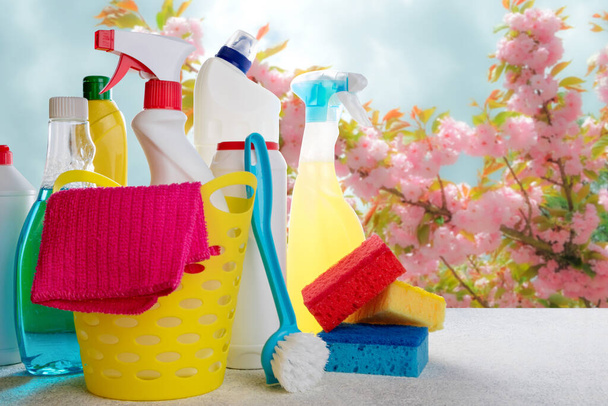 Cesta con herramientas de limpieza y productos sobre fondo borroso de primavera. Concepto de limpieza primavera
 - Foto, Imagen