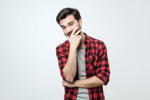 Homem adulto hispânico jovem olhando confiante para a câmera com sorriso e mão levantada no queixo. Pensar positivo
. - Foto, Imagem