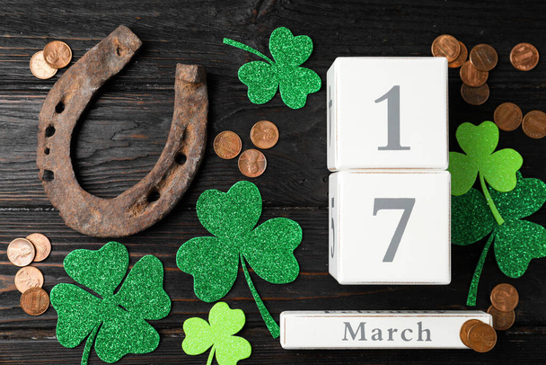 Flat lay composition with horseshoe and block calendar on black wooden background. St. Patrick's Day celebration - 写真・画像