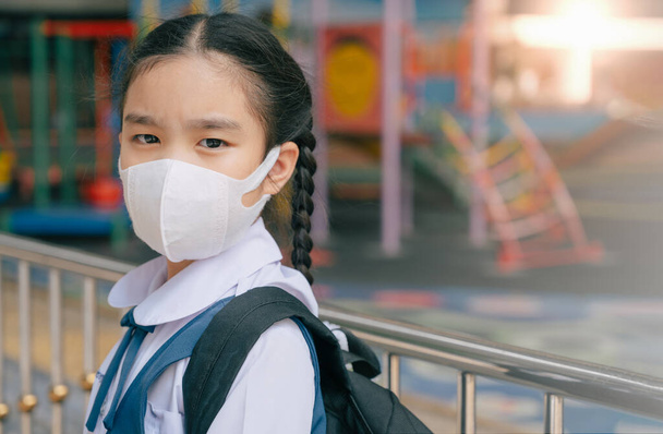 Retrato de los niños asiáticos niña usar máscara para proteger PM 2.5 polvo y la contaminación del aire. Retrato de estudiante tailandés con máscara de protección contra el mal tiempo, concepto de cuarentena del virus Corona, Covid-19 - Foto, imagen