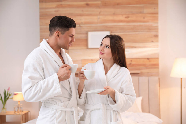 Happy couple in bathrobes with coffee in bedroom - Foto, afbeelding