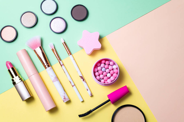 Makeup products and decorative cosmetics on color background flat lay. Set of professional decorative cosmetics. Fashion and beauty blogging concept. Top view, copy space - 写真・画像