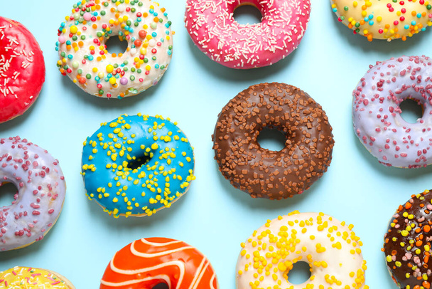 Delicious glazed donuts on light blue background, flat lay - Foto, Imagem