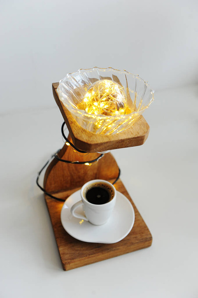 Ahşap damlatan kahve standı, v60 damlatıcı ve ışıktan yapılmış el yapımı bir sanat lambası. Alt güvertede bir fincan sade kahve. Uzmanlık alanı üçüncü dalga kahve konsepti. Kafenin içi için fikir - Fotoğraf, Görsel