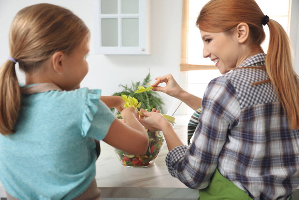 Mother and daughter cooking salad together in kitchen - Φωτογραφία, εικόνα