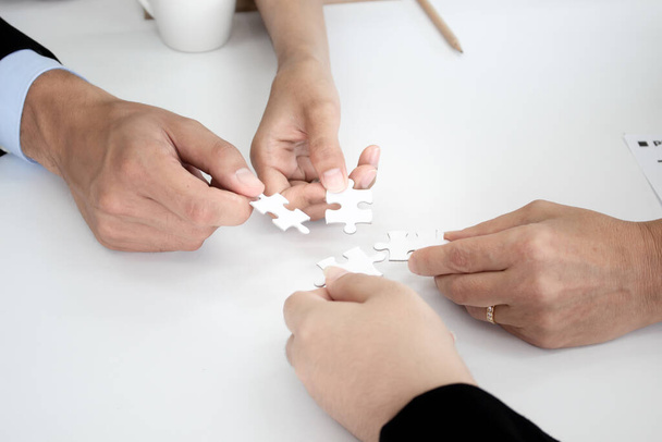 Mano sosteniendo los puzzles para que los empresarios trabajen juntos como un equipo. Concepto de planificación del trabajo en equipo. Primer plano de los empresarios que sostienen rompecabezas
. - Foto, Imagen