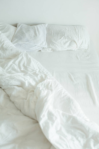 bed met witte lakens close-up heldere ochtend licht kopieerruimte - Foto, afbeelding