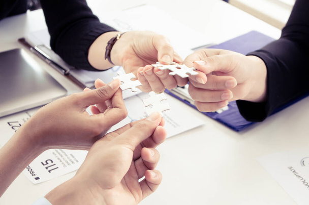 Hand holding the puzzles for the businessmen to work together as a team. Concept of planning work as a teamwork. Closeup of businesspeople holding jigsaw puzzle. - Photo, Image