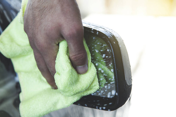 jonge werknemer man handdoek wassen auto - Foto, afbeelding