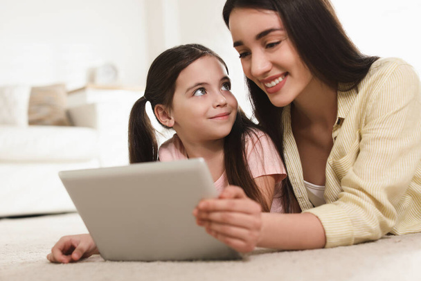 Madre e hija leyendo el libro electrónico juntas en casa
 - Foto, imagen