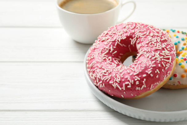 Yummy donuts with sprinkles on white wooden table, closeup. Space for text - Foto, afbeelding