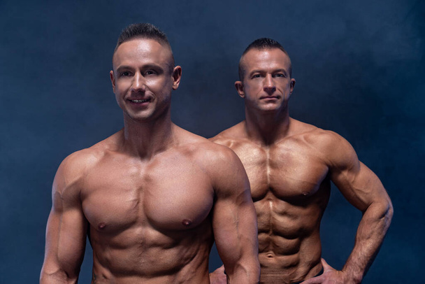 Dos hombres musculares aislados en el fondo negro. Fuerte macho desnudo torso abs
 - Foto, imagen