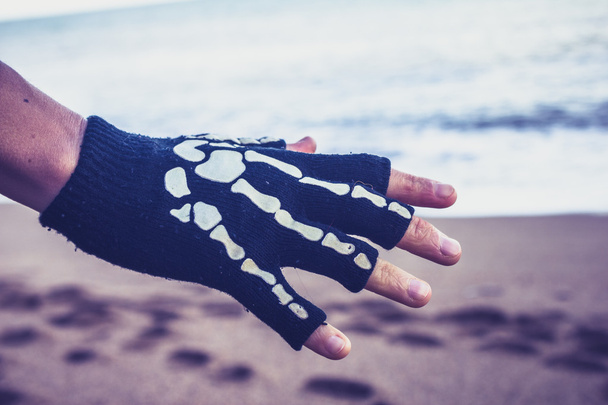 Woman wearing skeleton glove on the beach - Foto, imagen