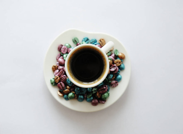 Coupe de café vue sur le dessus. Des grains de café multicolores perlés éparpillés autour. Concept d'idée de Pâques. Fond blanc isolé
. - Photo, image