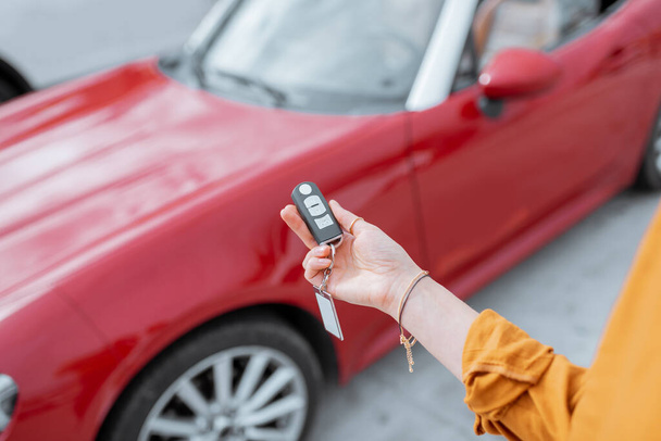 Woman holding keychain at the car parking - Photo, image