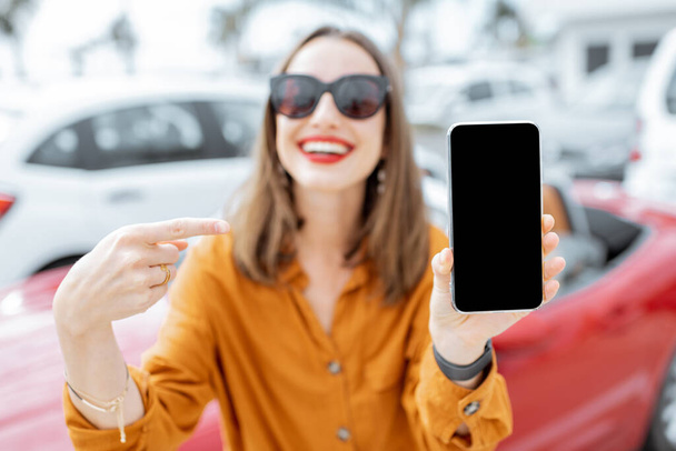 Mulher com telefone inteligente no estacionamento do carro
 - Foto, Imagem